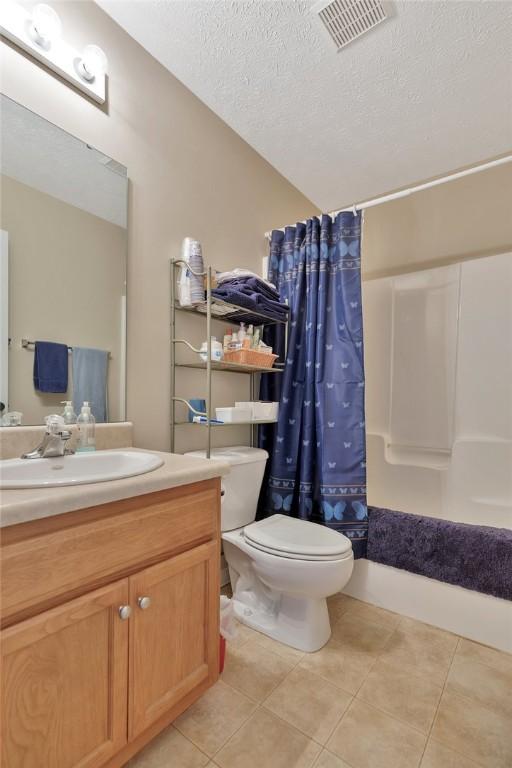 bathroom featuring vanity, visible vents, a textured ceiling, tile patterned floors, and toilet