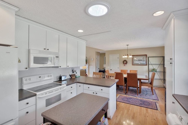 kitchen featuring dark countertops, white appliances, light wood-style floors, a peninsula, and white cabinets