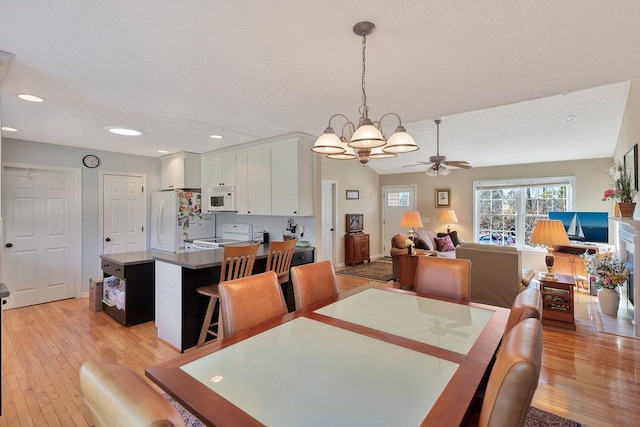 dining area featuring recessed lighting, light wood-style floors, and a textured ceiling