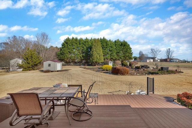 wooden terrace with cooling unit, a storage unit, outdoor dining area, and an outdoor structure