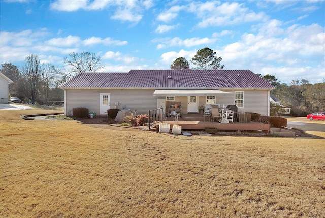 back of property with metal roof, a lawn, and a deck