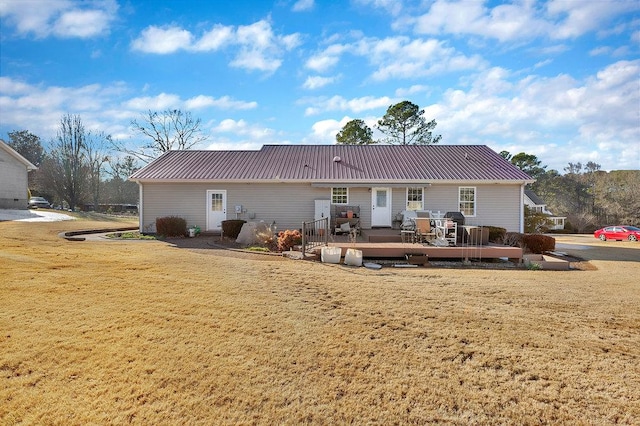 back of property with a wooden deck, a lawn, and metal roof