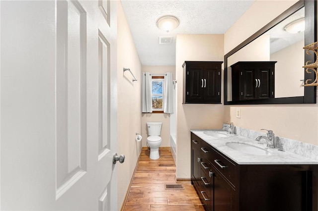 bathroom featuring hardwood / wood-style floors, vanity, toilet, and a textured ceiling