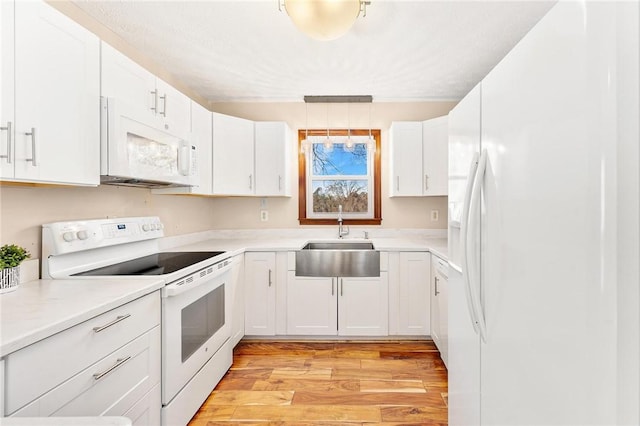 kitchen with white cabinets, pendant lighting, white appliances, and sink