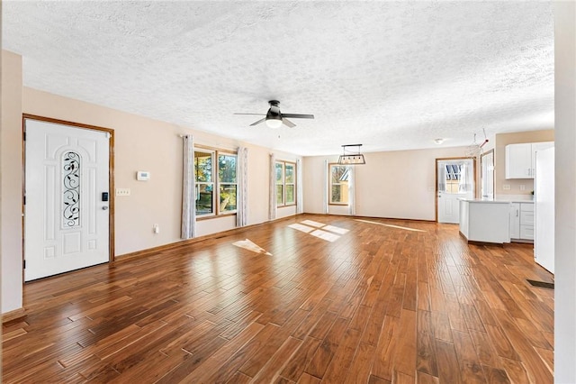 unfurnished living room with ceiling fan, a textured ceiling, and hardwood / wood-style flooring