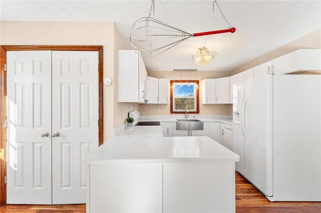 kitchen with white cabinetry, white fridge with ice dispenser, sink, stove, and pendant lighting