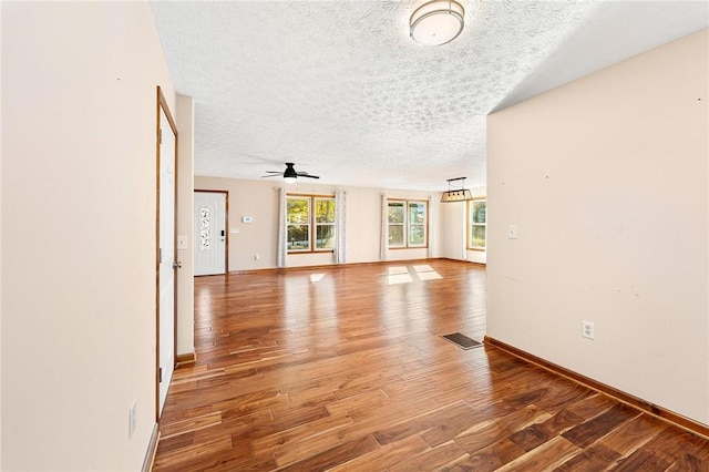 unfurnished living room featuring wood-type flooring, a textured ceiling, and ceiling fan