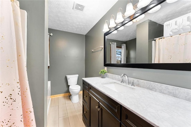 bathroom featuring vanity, a textured ceiling, and toilet