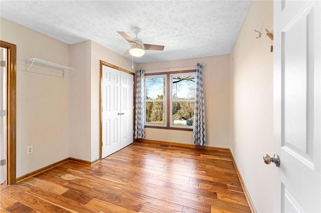 unfurnished bedroom with hardwood / wood-style floors, ceiling fan, a textured ceiling, and a closet