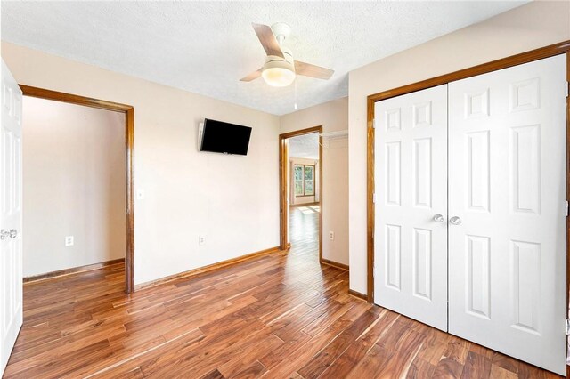 unfurnished bedroom with a closet, ceiling fan, hardwood / wood-style floors, and a textured ceiling