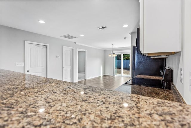 kitchen featuring stove, a chandelier, decorative light fixtures, wood-type flooring, and white cabinets