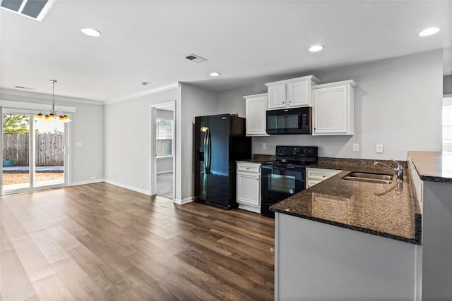 kitchen with sink, white cabinets, black appliances, and a notable chandelier