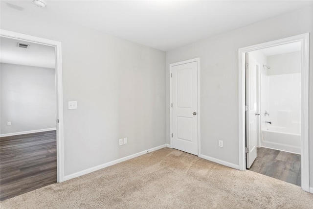 unfurnished bedroom featuring carpet floors and ensuite bathroom