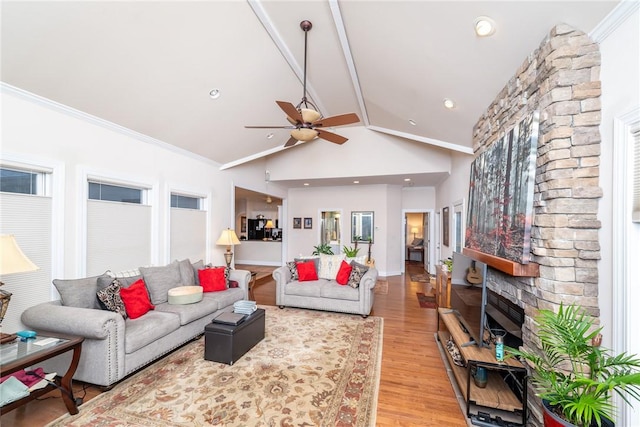 living room with a fireplace, lofted ceiling, ornamental molding, ceiling fan, and light wood-type flooring