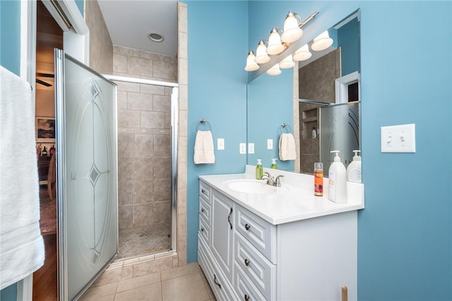 bathroom with a shower with door, vanity, and tile patterned floors