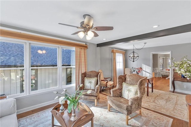 living room with ceiling fan with notable chandelier, light hardwood / wood-style floors, and beamed ceiling