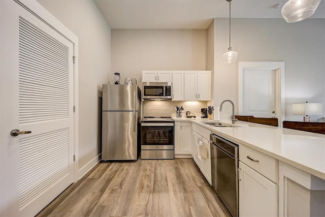 kitchen with stainless steel appliances, sink, white cabinetry, backsplash, and hanging light fixtures