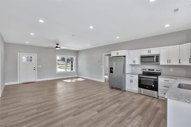 kitchen featuring appliances with stainless steel finishes, light stone countertops, ceiling fan, light hardwood / wood-style flooring, and white cabinetry