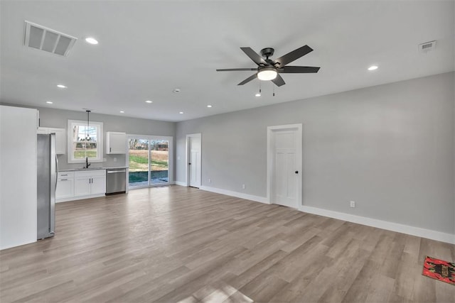 unfurnished living room featuring ceiling fan, light hardwood / wood-style flooring, and sink