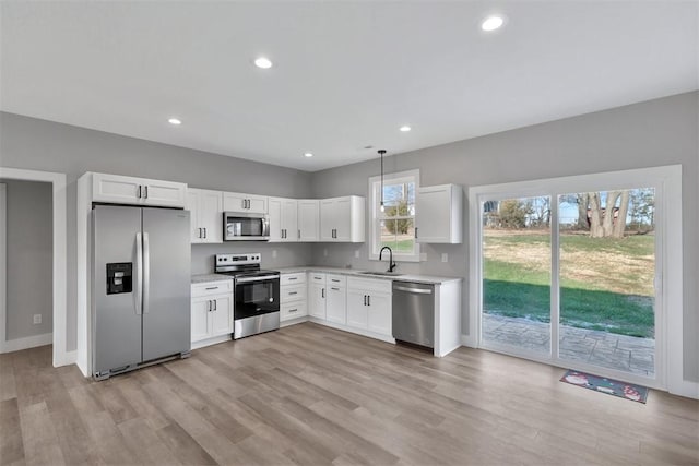 kitchen with sink, stainless steel appliances, decorative light fixtures, and white cabinets