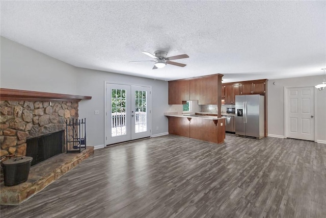 kitchen with a fireplace, french doors, kitchen peninsula, hanging light fixtures, and stainless steel fridge with ice dispenser