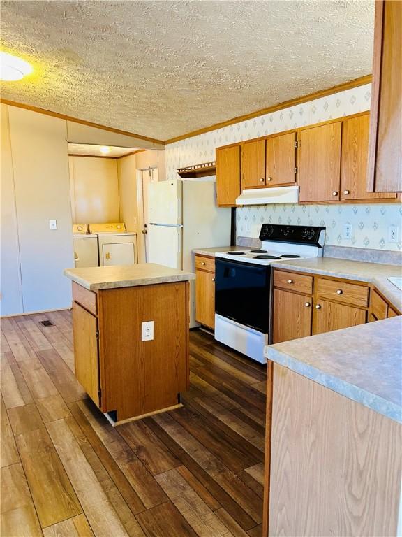 kitchen featuring white appliances, dark wood-type flooring, a textured ceiling, a center island, and washing machine and dryer