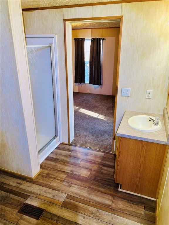 bathroom with an enclosed shower, vanity, and hardwood / wood-style flooring