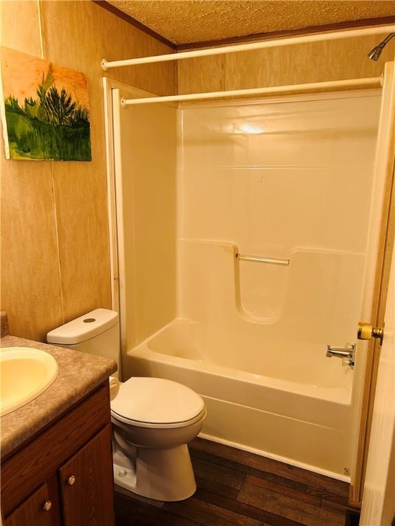 full bathroom featuring toilet, wood-type flooring, shower / washtub combination, wood walls, and vanity