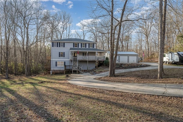 view of front of house featuring covered porch, a garage, and an outdoor structure