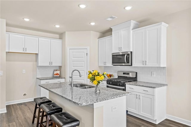 kitchen with stainless steel appliances, white cabinets, an island with sink, and sink