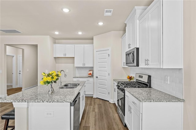 kitchen featuring sink, stainless steel appliances, white cabinetry, and a kitchen island with sink