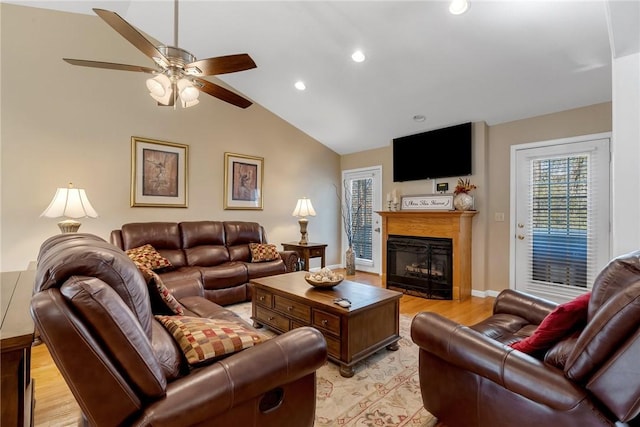 living room with light wood-type flooring, ceiling fan, and vaulted ceiling