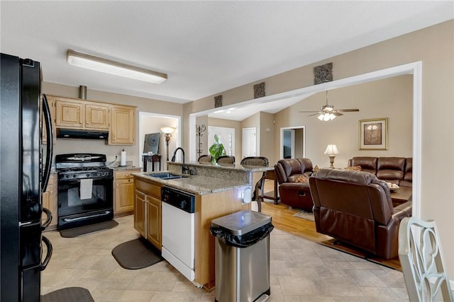 kitchen with sink, ceiling fan, black appliances, light brown cabinetry, and a kitchen island with sink