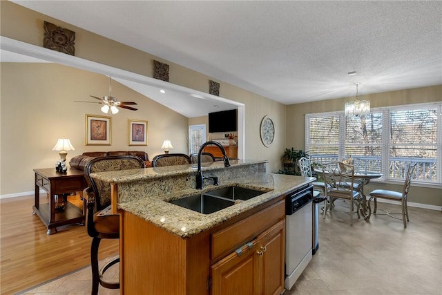 kitchen featuring sink, decorative light fixtures, a kitchen breakfast bar, stainless steel dishwasher, and a center island with sink