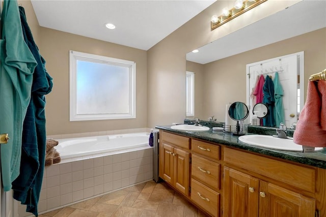 bathroom featuring tiled tub and vanity