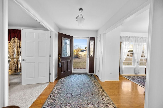 foyer entrance featuring baseboards, light wood-style flooring, and a healthy amount of sunlight