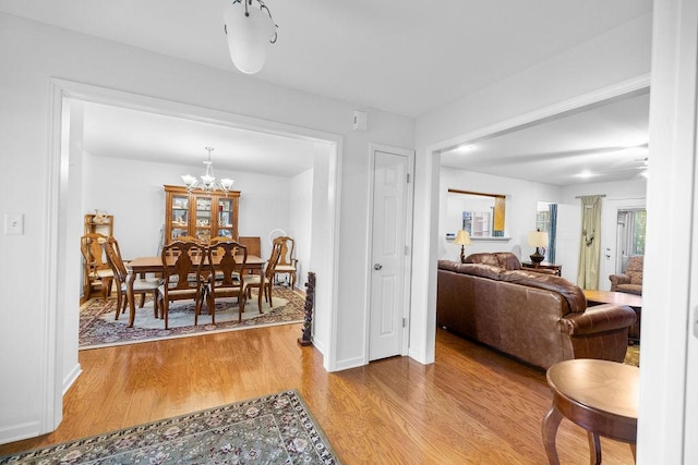 dining area with light wood-style flooring, a chandelier, and baseboards