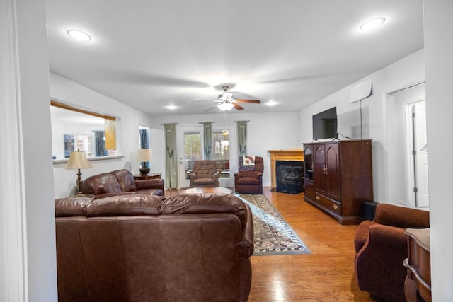 living room with light wood-style floors, a fireplace, and a ceiling fan