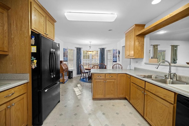 kitchen with a sink, black appliances, a peninsula, and light countertops