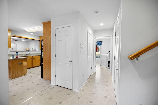 corridor with light floors, baseboards, a sink, and recessed lighting