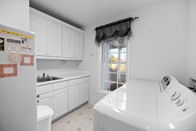 laundry room featuring baseboards, cabinet space, independent washer and dryer, and a sink