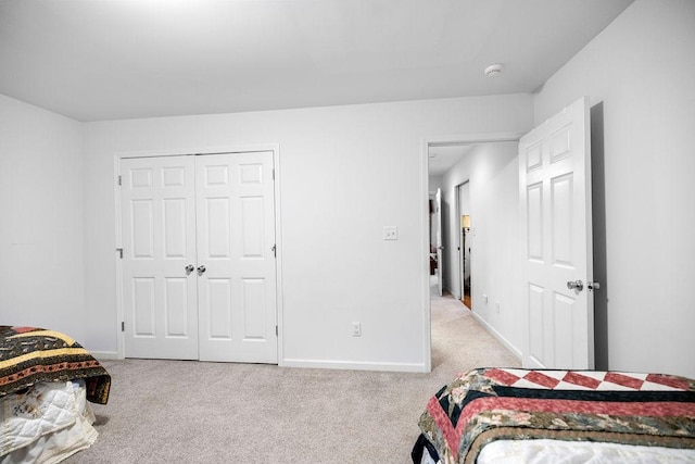 bedroom featuring light carpet, baseboards, and a closet