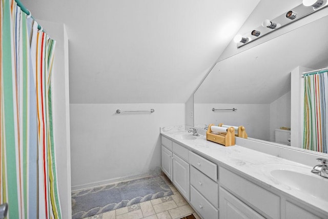 full bathroom with lofted ceiling, a sink, toilet, and double vanity