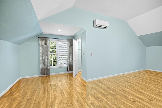 additional living space featuring lofted ceiling, a wall mounted air conditioner, and light wood-style floors