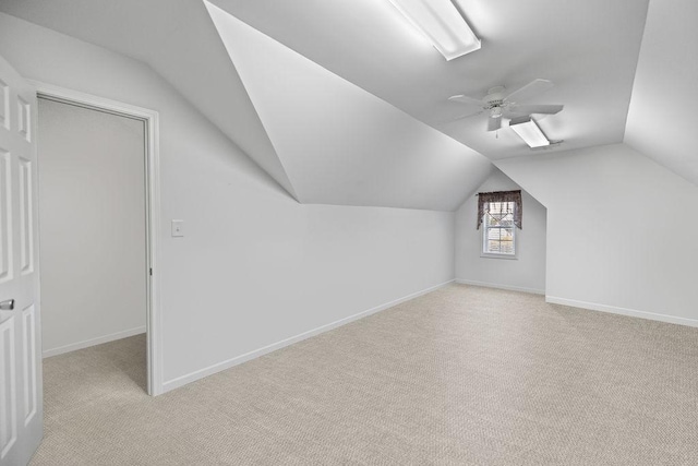 bonus room featuring light carpet, vaulted ceiling, a ceiling fan, and baseboards