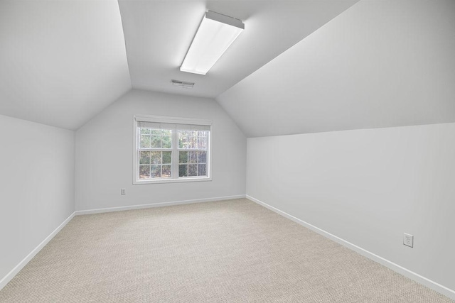 additional living space featuring vaulted ceiling, light carpet, visible vents, and baseboards