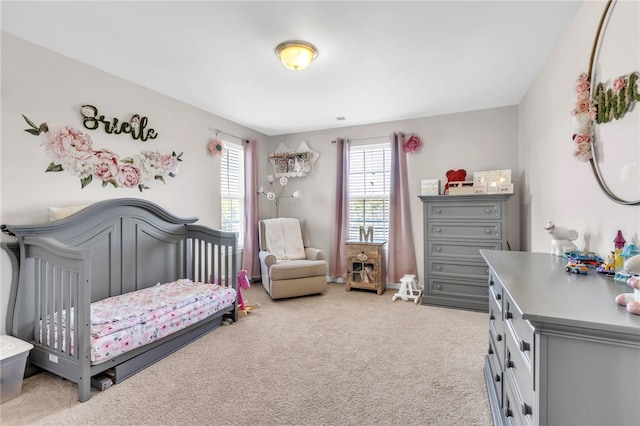 bedroom featuring a nursery area and light carpet