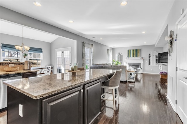 kitchen with dishwasher, decorative light fixtures, a kitchen island, an inviting chandelier, and dark hardwood / wood-style flooring