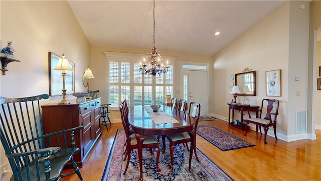 dining area with a chandelier, lofted ceiling, and hardwood / wood-style flooring