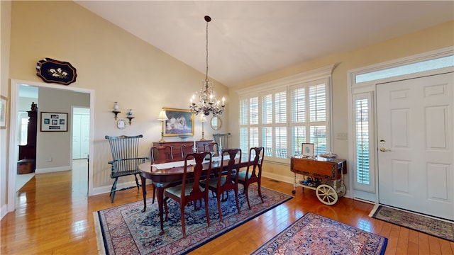 dining area with lofted ceiling, a notable chandelier, and hardwood / wood-style floors